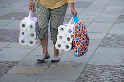woman carrying two large packs of loo roll