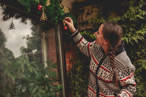 A woman in a fair isle sweater hangs up christmas ornaments. Dealing with loneliness around the holi...