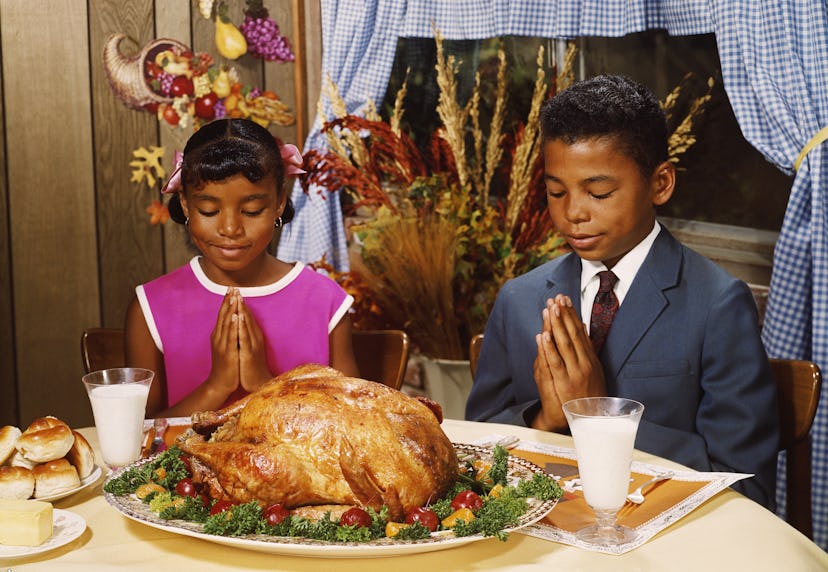 Siblings praying before Thanksgiving dinner.