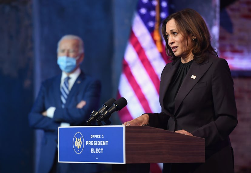 Kamala Harris giving a speech with Joe Biden blurred in the background