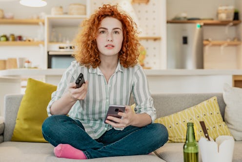 A woman holds her phone while watching TV. Divided attention can be fun, but it can also harm memory...