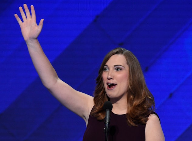 Sarah McBride smiling and waving in a black sleeveless dress