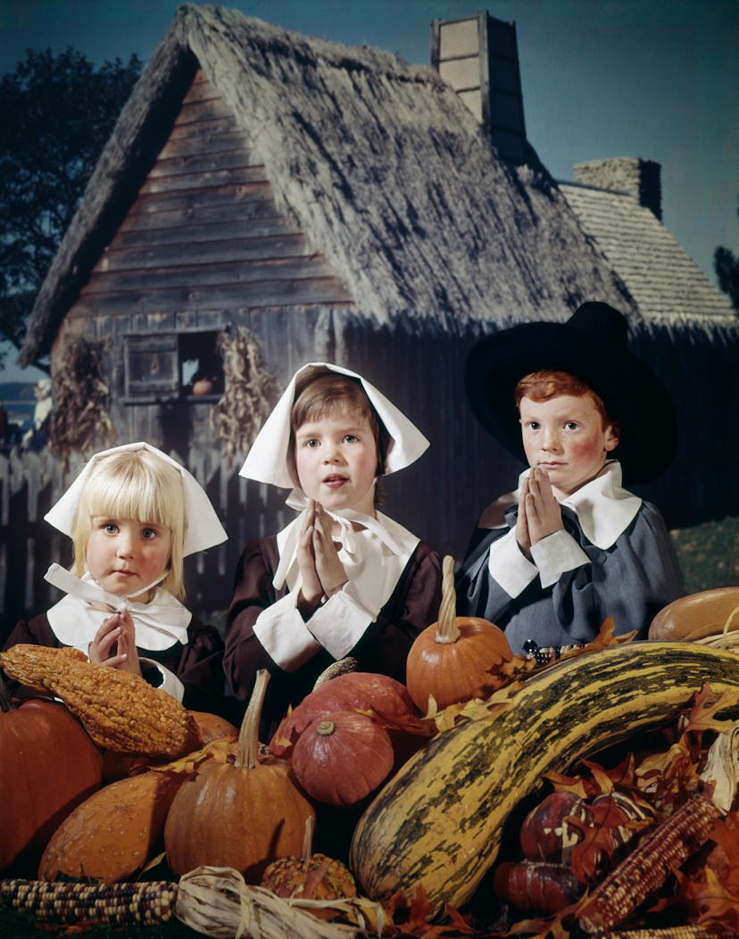 Children posing as pilgrims with pumpkins.