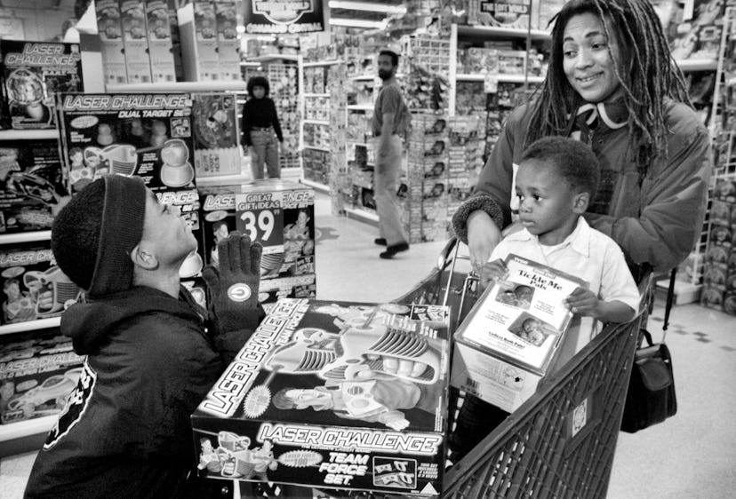 A mother shops with children at a toy store for a Tickle Me Elmo.