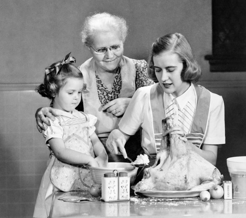 A mother, grandmother, and daughter all stuff a turkey.