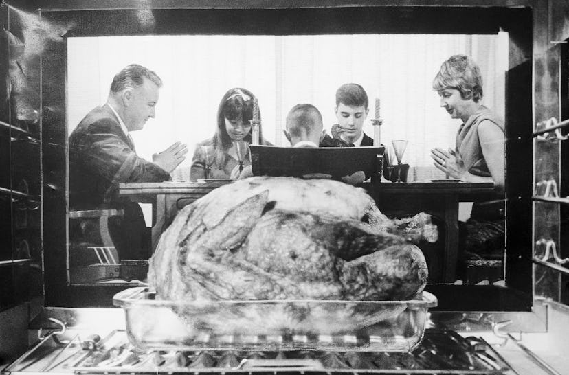 A turkey in an oven with family in the background.