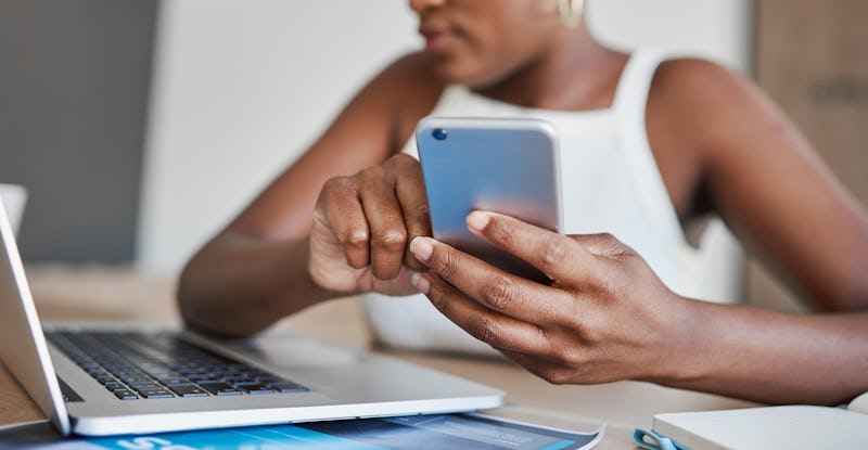 A woman tweets on her phone while looking at her computer. Twitter announced Fleets, disappearing Tw...