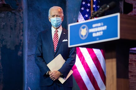 Joe Biden with a mask over his mouth, holding a white folder