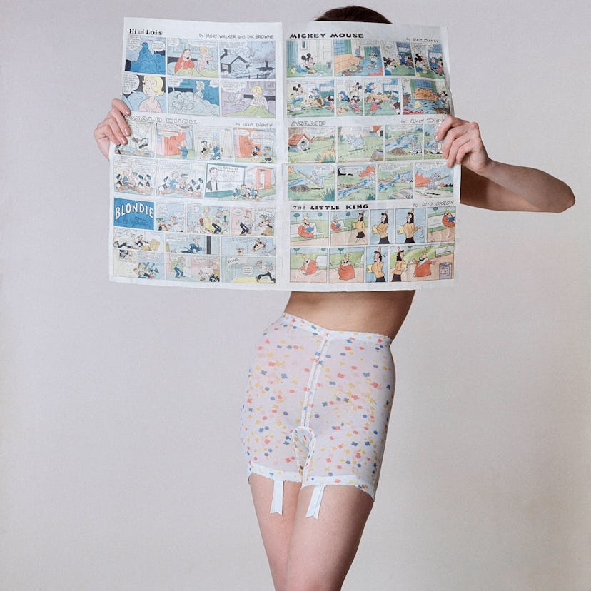 A model wearing polka dot pants while covering her face and upper body with a mickey mouse comic
