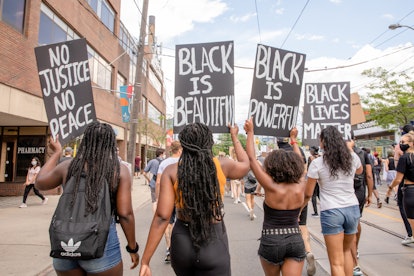 Protestors walking with signs that say black is beautiful, black lives matter, black is power and no...