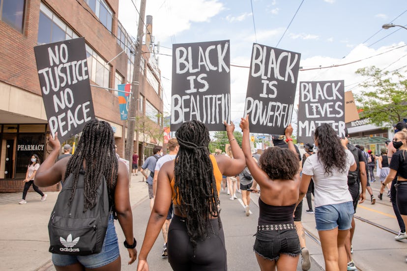 Protestors walking with signs that say black is beautiful, black lives matter, black is power and no...