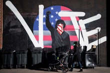 Graffiti of a man holding his fist in the air with the words vote and the american flag behind him