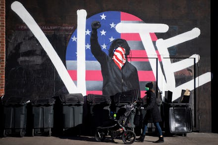 Graffiti of a man holding his fist in the air with the words vote and the american flag behind him