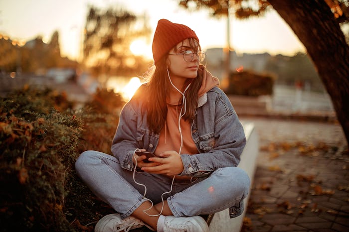 Woman sitting in the park on an autumn day just as the sun is setting