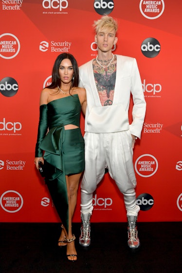 Megan Fox in a green dress and Machine Gun Kelly in a white suit on the AMAs red carpet event lookin...