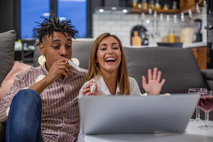 A couple sits at their computer, celebrating a virtual wedding.