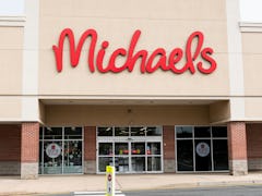 A Michaels store front has "buy online" signs on the windows on a sunny day. 