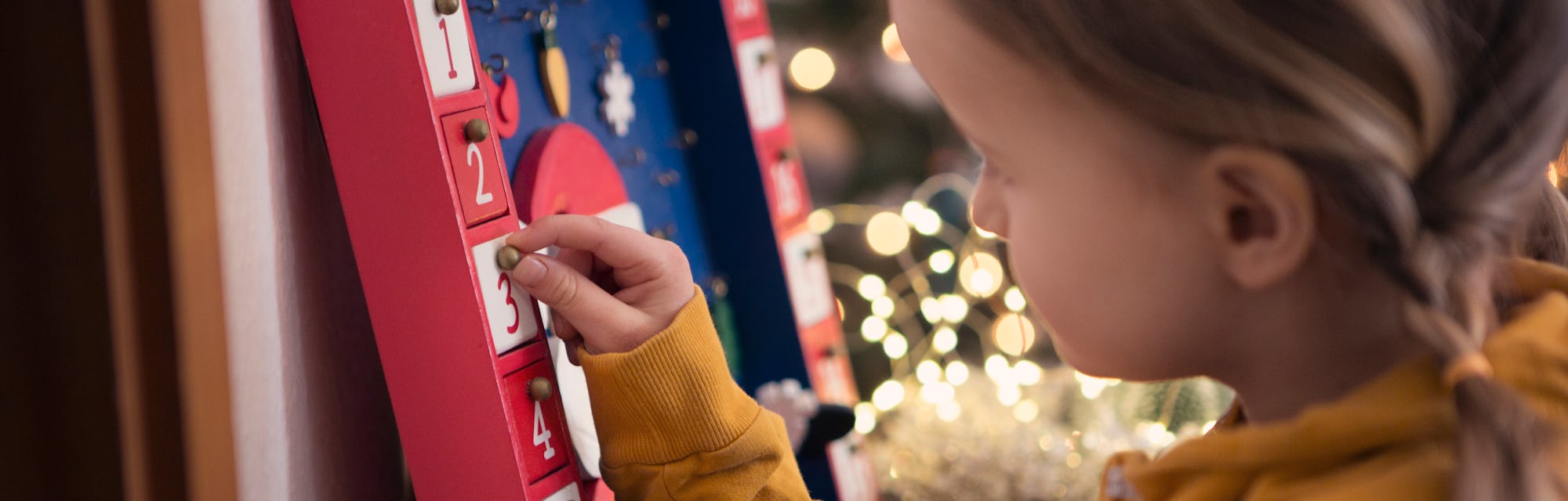 little girl opening door on advent calendar