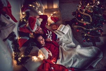 A couple snuggles in their festively-decorated home for the holidays to watch Christmas movies.
