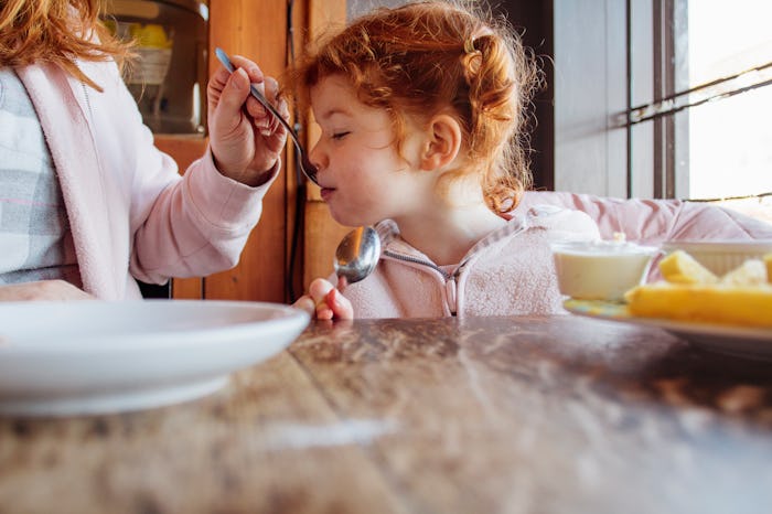 little girl being fed soup