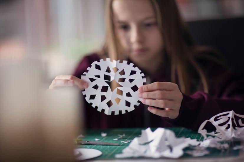 A girl cutting out a paper snowflake