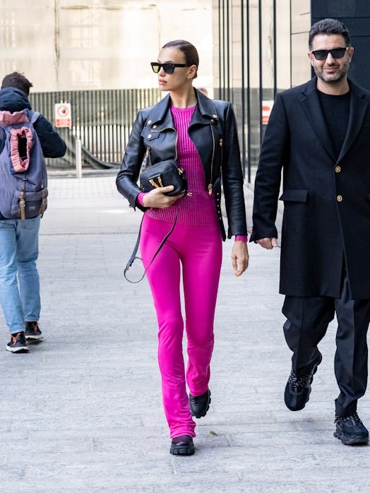 Irina Shayk walking the street in a hot pink co-ord set, cropped moto jacket paired with combat boot...