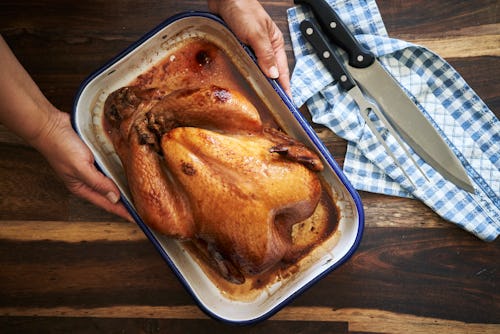 A man putting a tray with turkey on the Thanksgiving table.