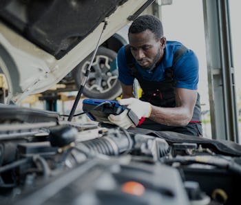 Auto technician looking under the hood of a car.