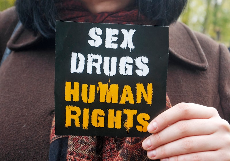 A person holds up a small sign that reads, "sex, drugs, human rights." Decriminalizing drugs in the ...