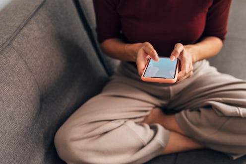 A woman with a phone in her hand contemplates how to make change on instagram with a small following
