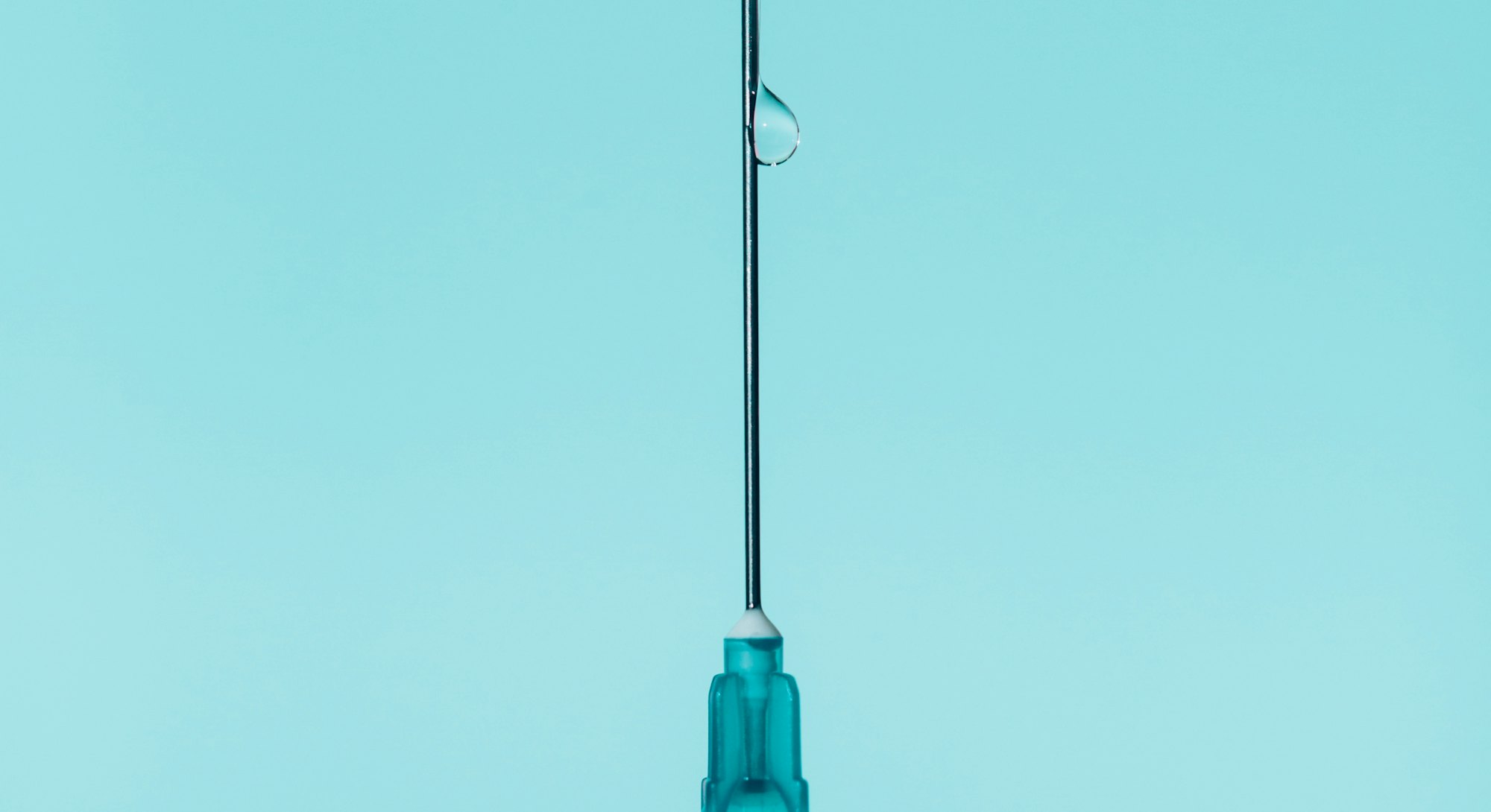 A vaccine on a blue backdrop with a drop of coronavirus vaccine.
