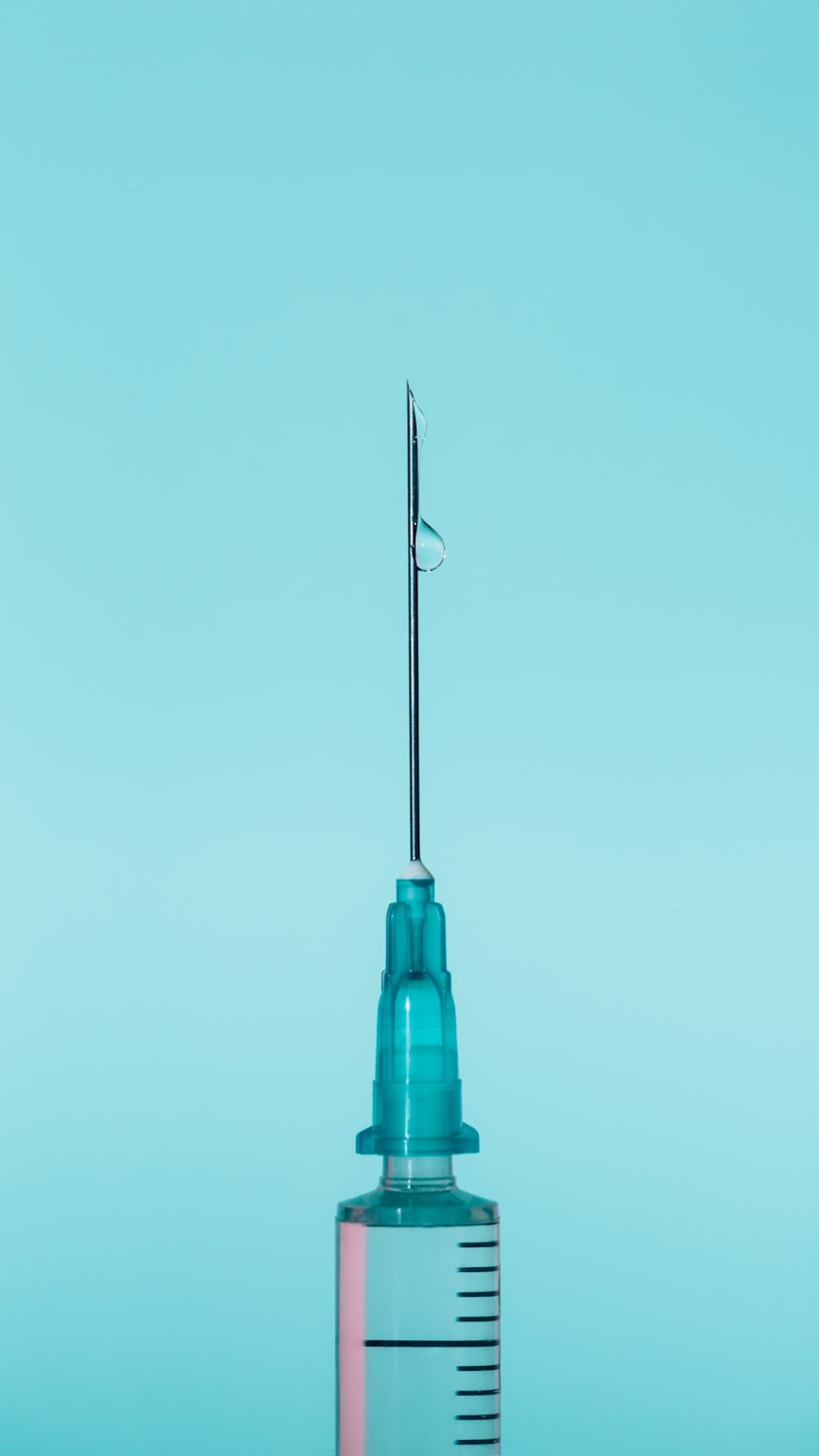 A vaccine on a blue backdrop with a drop of coronavirus vaccine.