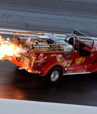 Red truck spitting flames out of its exhaust on a race track.