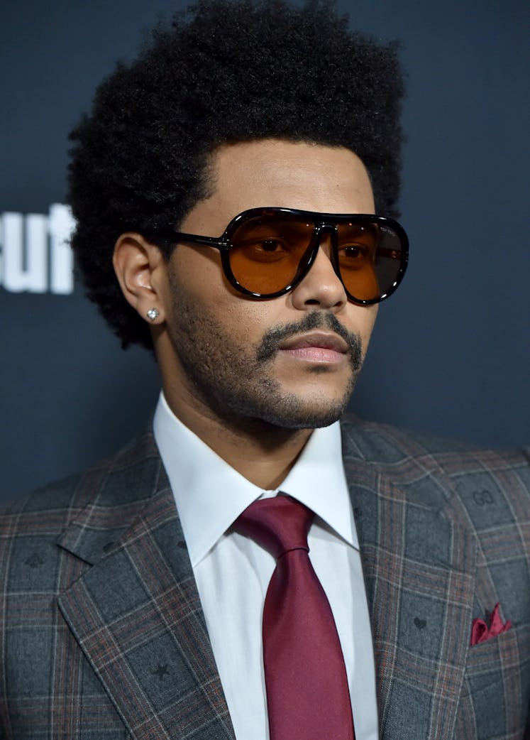 The Weeknd hits the red carpet wearing black sunglasses.
