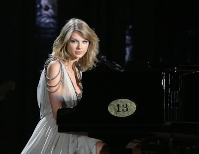 Taylor Swift on stage in a long silver dress