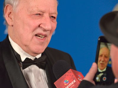 Werner Herzog wearing a black suit and a white shirt while being interviewed  about Elon Musk