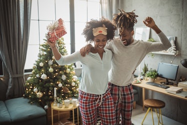 A happy couple dances in their living room in their Christmas loungewear.
