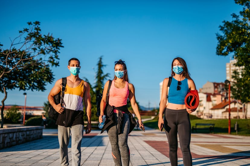 A group of masked friends walks to yoga in a park. Women worked out more than men in 2020.