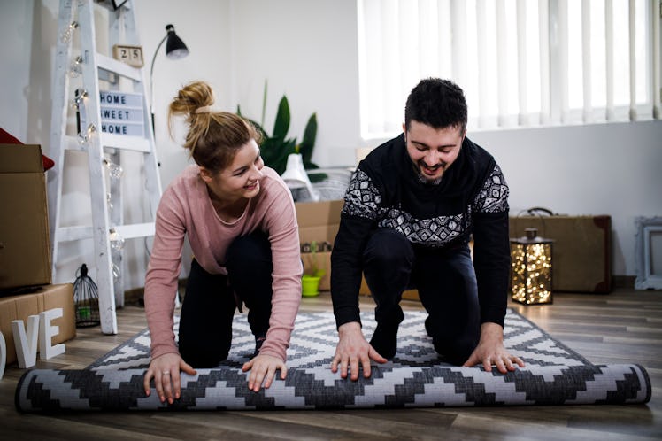 A couple roll out a new rug in their living room after being inspired by TikTok rug tufting videos