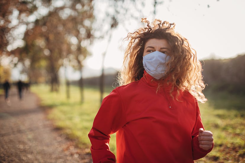 A woman with curly hair runs on a country road. Women logged significantly more workouts in 2020 ove...