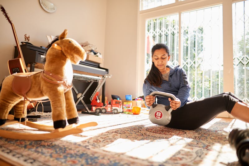 A woman does kettlebell exercises in her childhood bedroom. These workouts like kettlebell routines ...