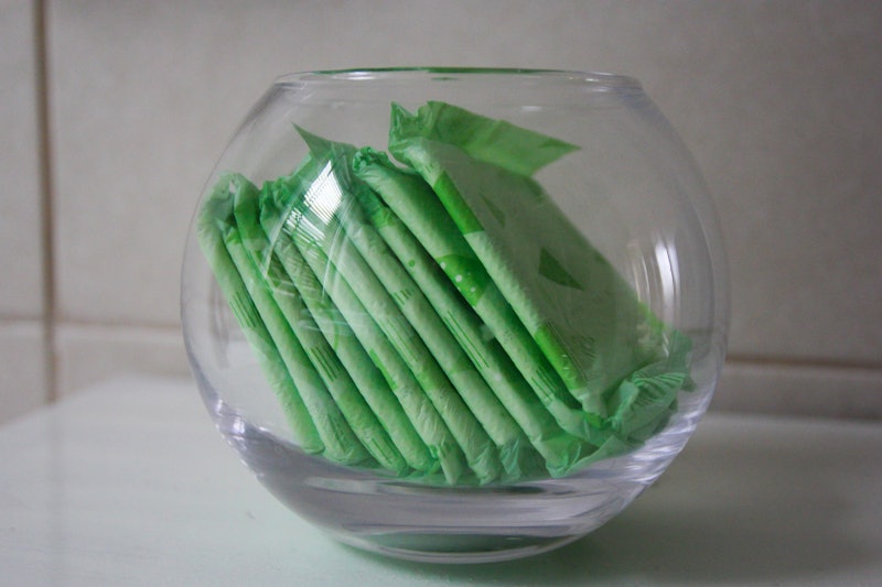 A fish bowl containing several green packs of tampons