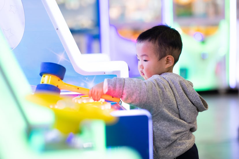 boy playing arcade game in article about old wives' tales about babies born on new year's day