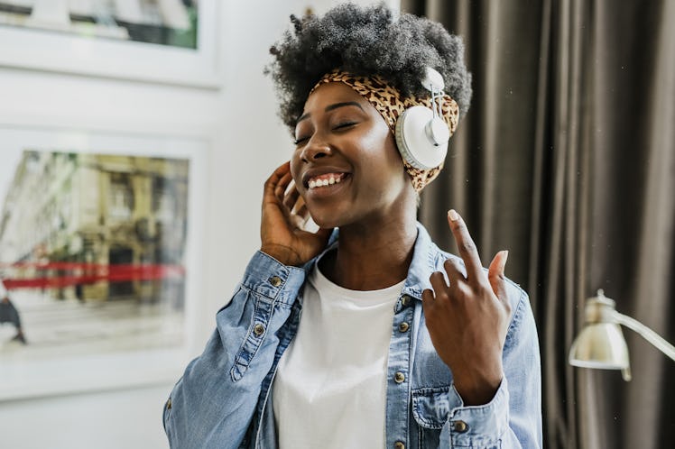 A happy woman with headphones on listens to music, which is great when you're alone in snow on a win...