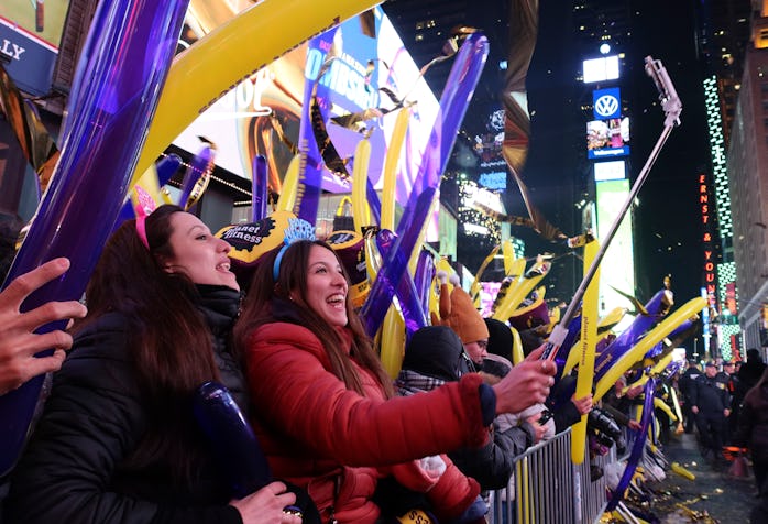 People can be seen holding purple and yellow balloons in Times Square, New York City. 