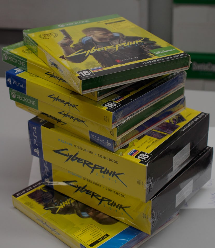 Physical copies of the game 'Cyberpunk 2077' stacked on a table. 