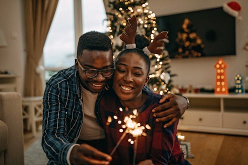 A happy couple holding a sparkler while hugging as a way of representing New Year's Eve ideas for ne...