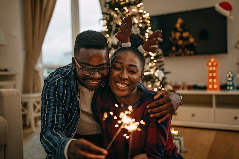 A happy couple holding a sparkler while hugging as a way of representing New Year's Eve ideas for ne...