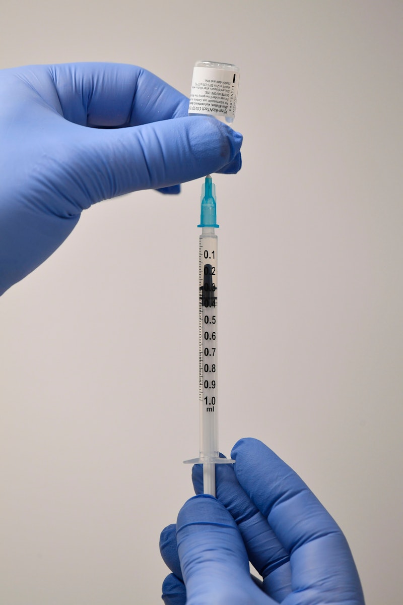 A healthcare worker takes a dose of the COVID-19 vaccine from a vial. Doctors explain why you need t...