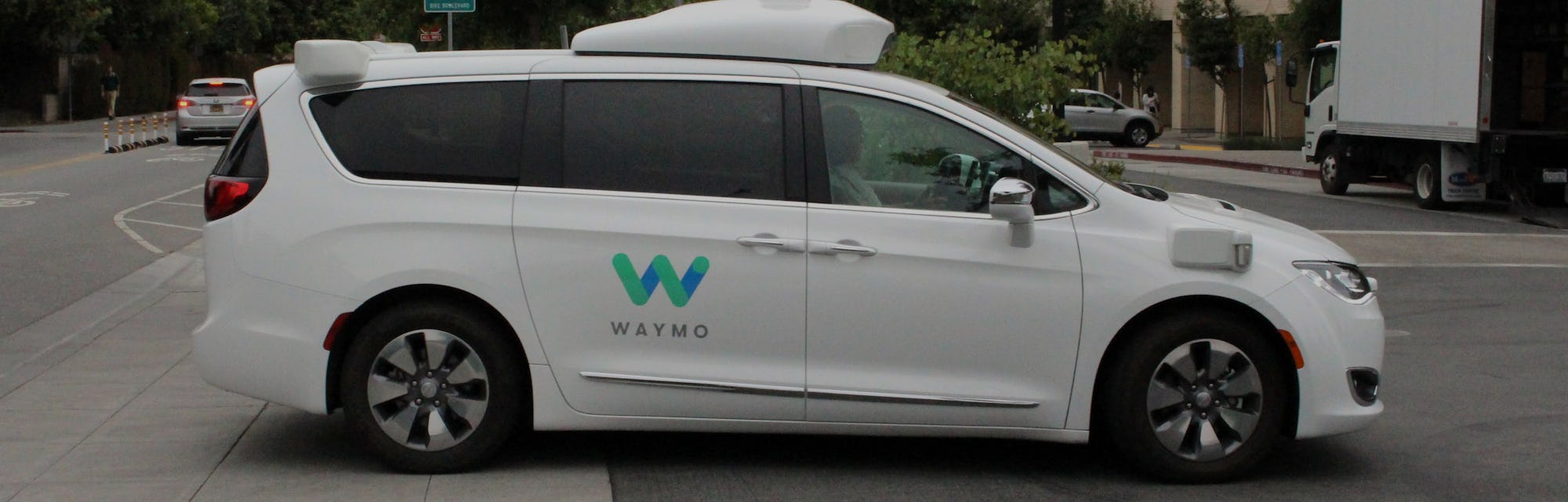 A Waymo autonomous van entering a parking lot. 